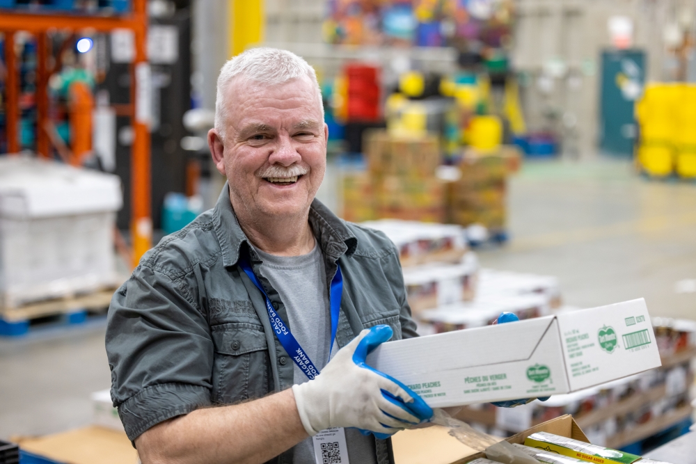 Volunteer holding fresh produce in the Calgary Food Bank warehouse